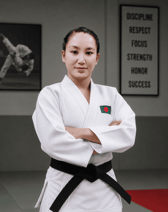 Masinu Marma in a white judo gi with black belt, standing in a dojo